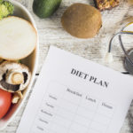 Bespoke diet plan sheet on a table next to a bowl of vegetables.
