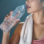 Closeup of a woman drinking a large bottle of water after exercising. Used for a 3D facial treatment blog.