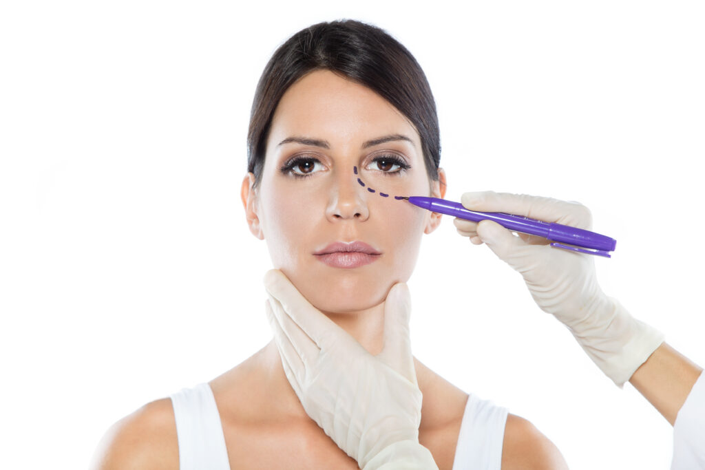 Portrait of plastic surgeon drawing dashed lines on her patient's face.