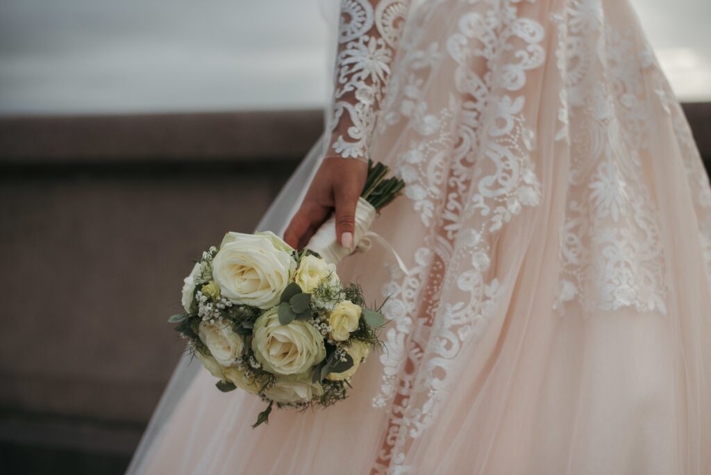 The bride wearing a beautiful wedding dress and holding her wedding day's bouquet of beautiful roses after bespoke treatments 